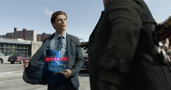 A man in a suit looks up at a large figure, revealing a glowing blue digital interface inside his jacket.