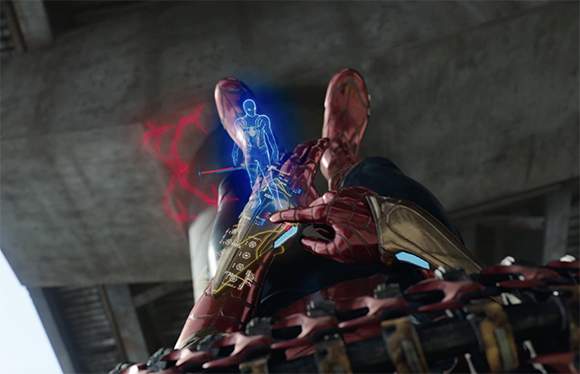 Low-angle view of a red and gold armored hand holding a glowing blue holographic figure.
