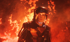 A person wearing dark, structured armor stands in front of a bright, fiery orange background.