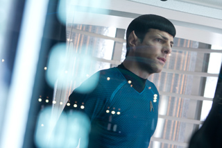 A man with pointed ears and dark hair wearing a blue uniform looks intensely to the side.