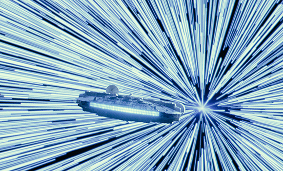 A large spaceship traveling through a tunnel of bright blue and white light streaks.