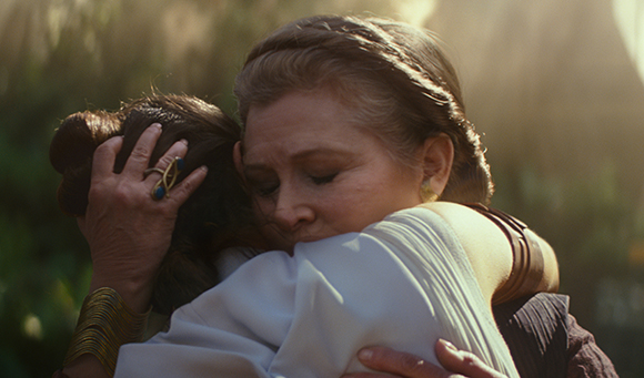 An older woman with light brown hair closes her eyes while hugging a person with dark hair.