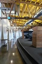 An office space featuring high wooden ceilings, exposed ductwork, and a curved gray carpeted platform.
