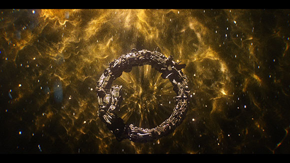 A large, dark, ring-shaped mechanical structure floating amidst a swirling golden nebula and stars.