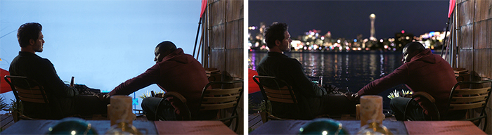 Two men sit at a table facing a waterfront, one side in daylight and the other at night with city lights.