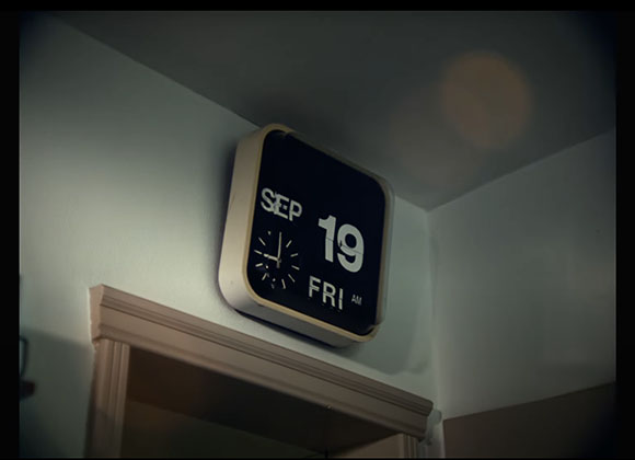 A square digital flip clock mounted on a white wall showing September 19, Friday.