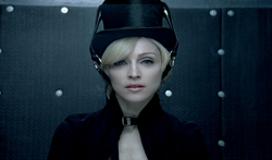 A person with blonde hair wearing a black top hat and a high-collared black garment.