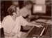 A person in a light-colored shirt reaches toward a keyboard at a desk.