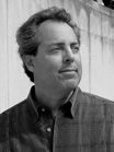 Black and white portrait of a man with wavy hair looking toward the side.