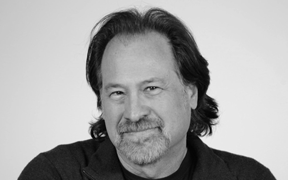 Black and white headshot of a middle-aged man with dark hair and a goatee smiling slightly.