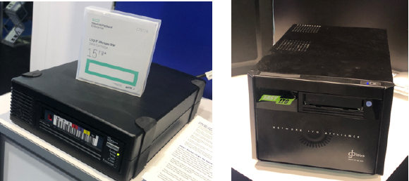A black LTO data cartridge drive and a translucent white storage case containing a cartridge.