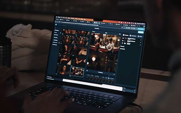 A person's hands typing on a laptop displaying a video editing software interface with multiple clips.