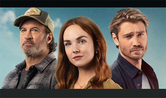 A man with a beard and cap, a woman with red hair, and a man with light brown hair against a blue sky.