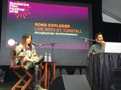 KT Tunstall sits on a director's chair on stage at Sundance Film Festival 2016, with a screen behind her showing "Song Explod