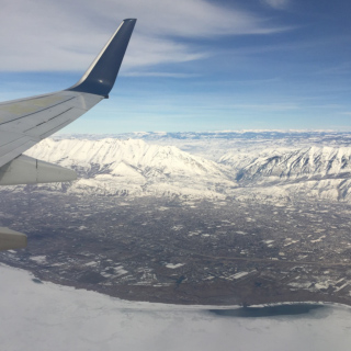 Aerial view of a city nestled between snow-covered mountains, seen from an airplane.