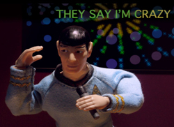 An action figure in a blue uniform holding a microphone against a dark, patterned background.