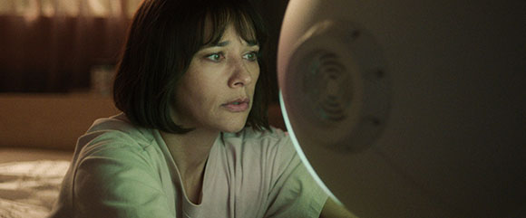 A woman with dark hair looks intently at a large, rounded white object in a dimly lit room.