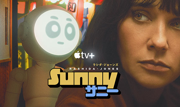 A close-up of a woman's face next to a small, round-headed robot with large eyes.