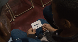 A person holds a small white card with the name 'Anthony' printed in black ink.