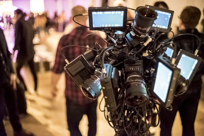 A professional video camera rig with several attached monitors and lenses in a dimly lit room.