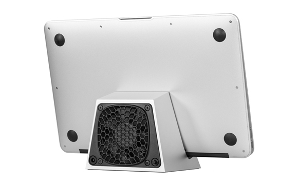 A silver tablet resting on a small, wedge-shaped black and silver speaker stand against a white background.