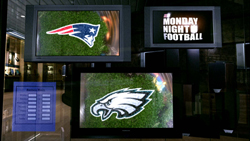 Three monitors showing football graphics and a Monday Night Football logo in a dark setting.