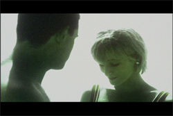 A man and a woman in profile, looking downward against a bright, pale background.