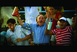 A group of people cheering and celebrating with drinks and falling confetti.