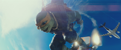 A humanoid turtle wearing an orange mask skydives through a bright blue sky near a passing airplane.