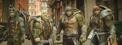 Four large anthropomorphic turtles walking together through a narrow urban alleyway.