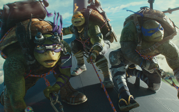 Three anthropomorphic turtles wearing masks and gear crouch on a metallic platform against a blue sky.