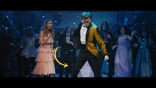 People in formal attire dancing and celebrating amidst falling blue confetti in a dimly lit room.