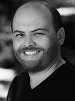 Black and white headshot of a smiling man with short hair and a beard.