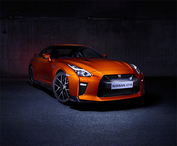 An orange Nissan GT-R sports car parked in a dimly lit concrete garage.