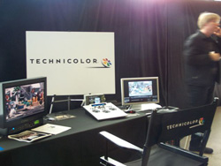 A Technicolor booth displays monitors, a control panel, and a branded chair, with a person standing to the right.