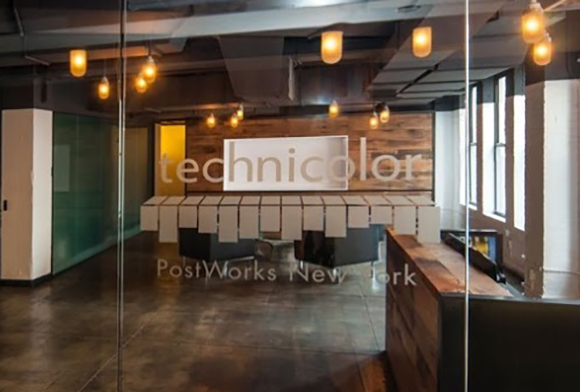Technicolor PostWorks New York office interior with wooden walls, pendant lights, and a long white table.
