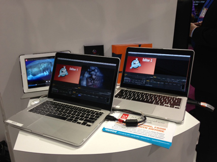 Two silver laptops and a white tablet displaying video editing interfaces on a white circular table.