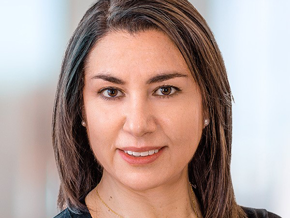 A woman with dark brown hair and brown eyes smiling at the camera.