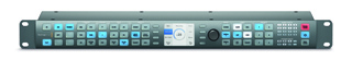 A dark grey rack-mounted control panel featuring a central digital screen and rows of blue and white buttons.