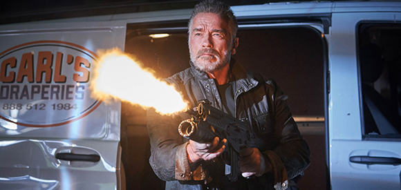 A man with a beard fires a handgun with a large muzzle flash from the side door of a white van.