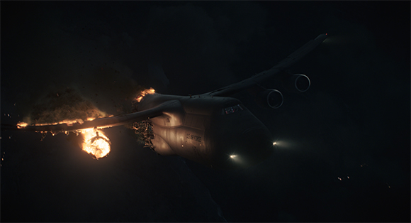 A large military transport aircraft with flames and smoke erupting from its left wing in a dark night sky.