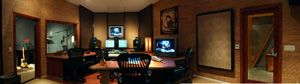 A recording studio control room with computer monitors, mixing equipment, and acoustic wall panels.