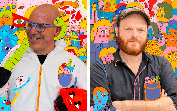 A bald man in blue glasses and a bearded man in a cap pose before vibrant, abstract character murals.