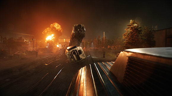 A train car tilts on tracks near a large orange explosion at night.