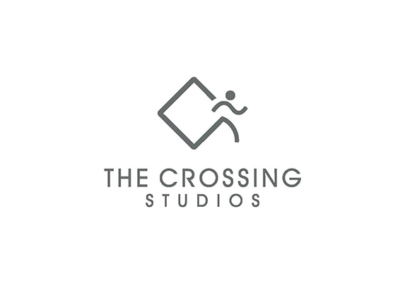 Gray logo of a diamond shape and a stylized human figure above the text THE CROSSING STUDIOS.