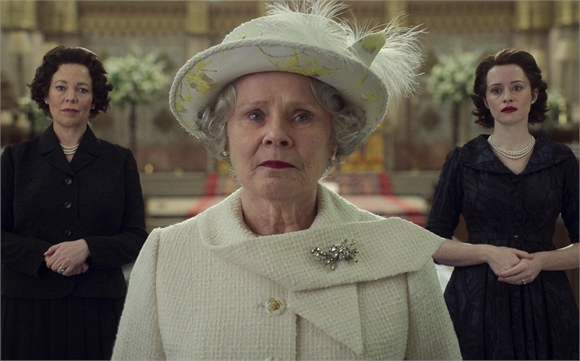 An older woman in a white hat and coat stands centered between two younger women in dark formal dresses.