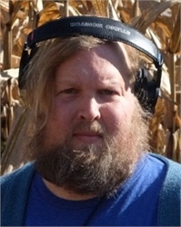 A man with long blonde hair and a thick beard wearing black over-ear headphones.