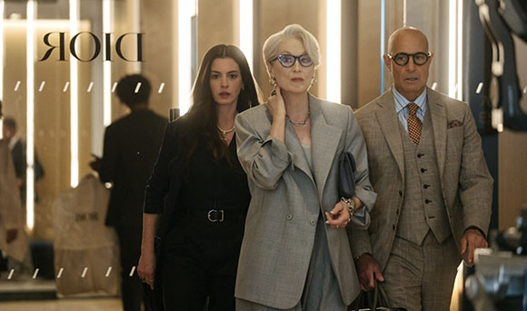 Three people in elegant clothing stand together in a brightly lit, modern room.