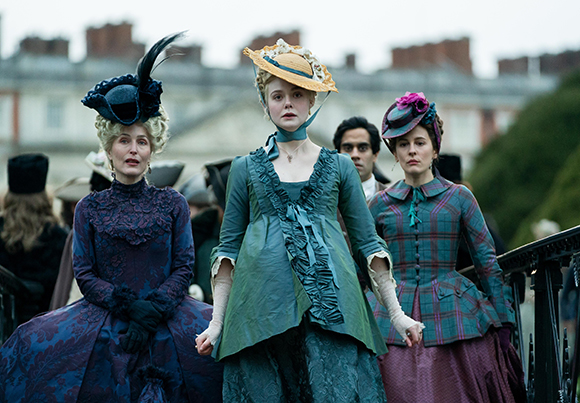 Three women in ornate 19th-century dresses and decorative hats walking through an outdoor setting.