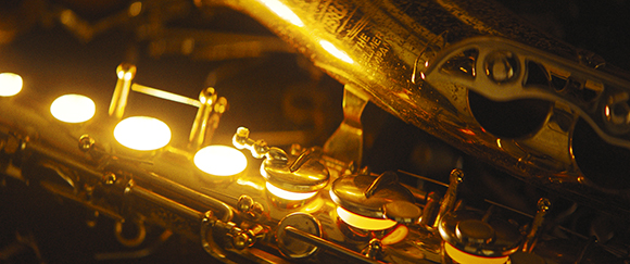 Close-up of the golden keys and body of a saxophone illuminated by warm, glowing lights.